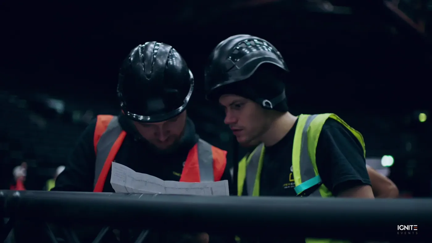 Two technicians in hard hats checking a plan during the build