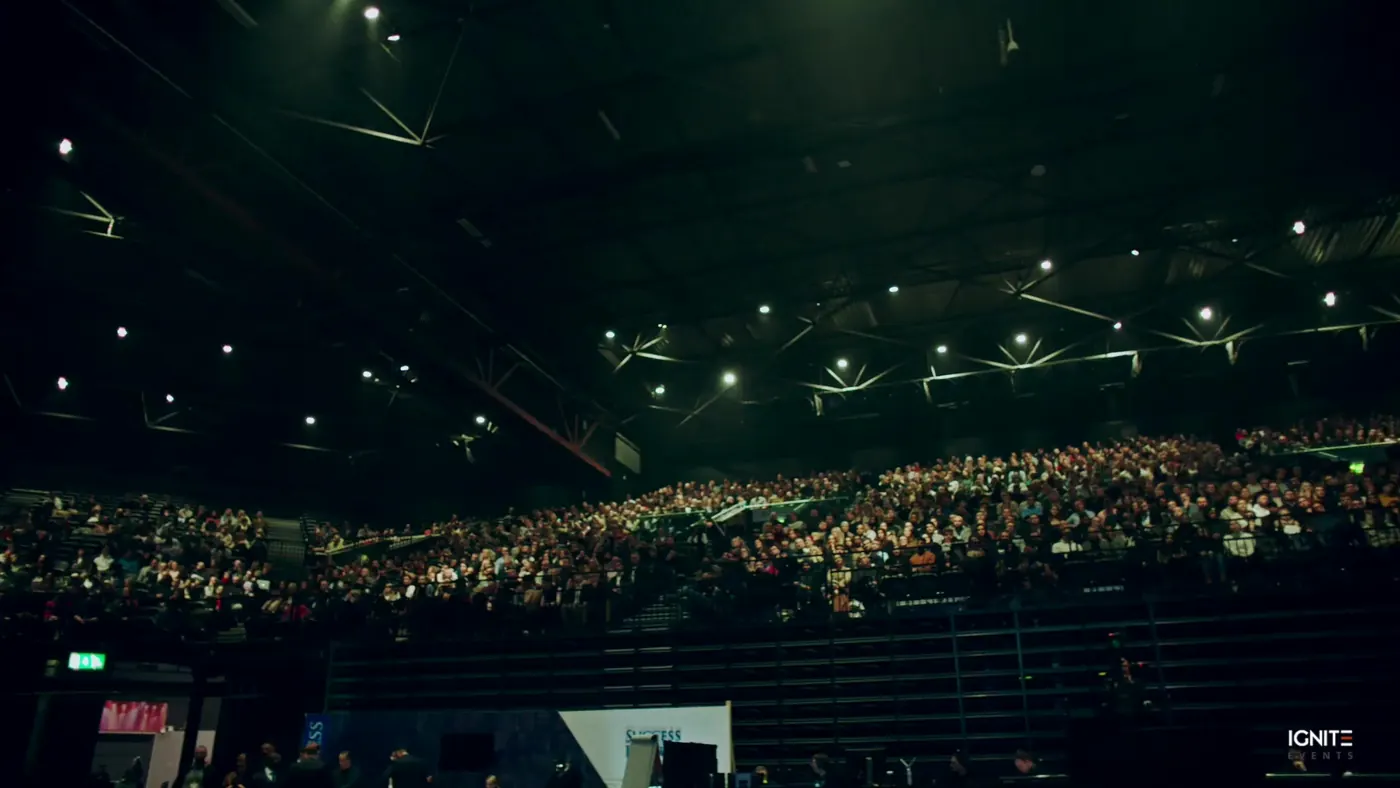 A packed arena audience seen from the stage end