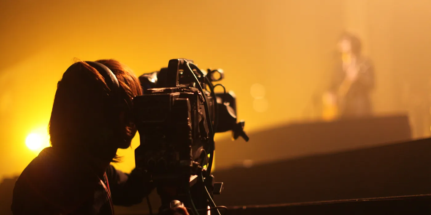 Camera operator filming a live performance through stage haze
