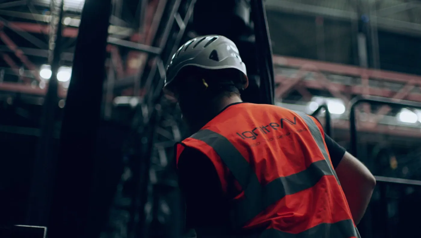 IGNITE crew member in a branded hi-vis vest and helmet working backstage in an arena