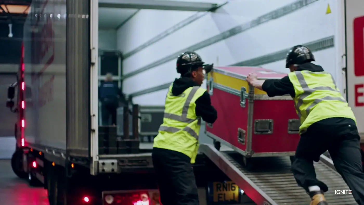 Crew pushing a flight case up the ramp of a truck for transport