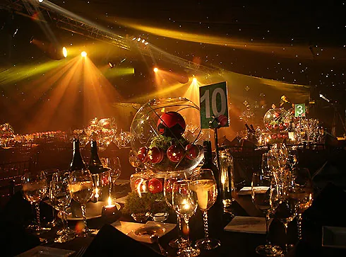 Dressed gala table with candlelit centrepiece under warm beam lighting
