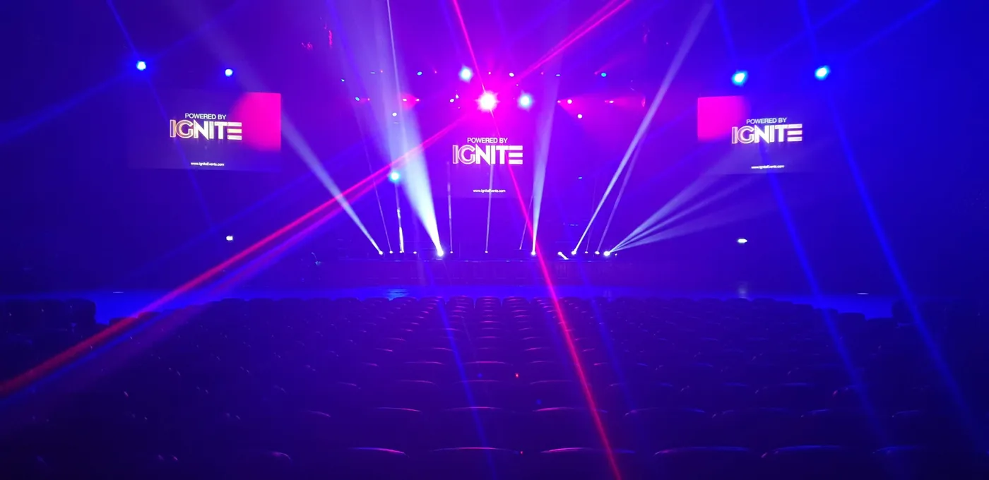 Arena stage lit in pink and blue with 'Powered by IGNITE' on the screens