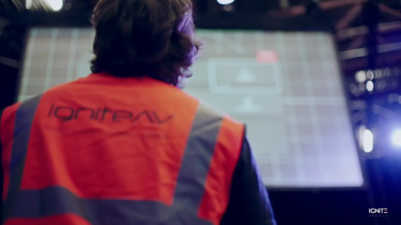 IGNITE technician in a branded hi-vis vest at a control screen