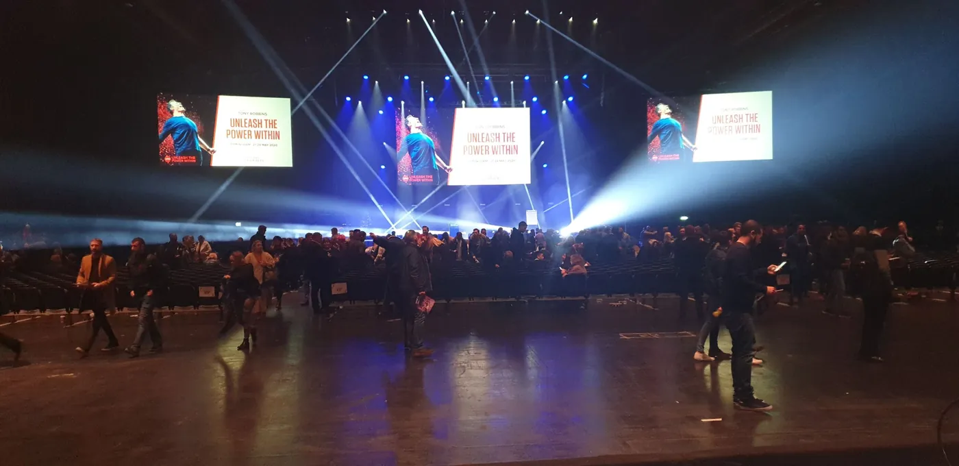 Arena floor after a session, with beam lighting and three large screens above the stage